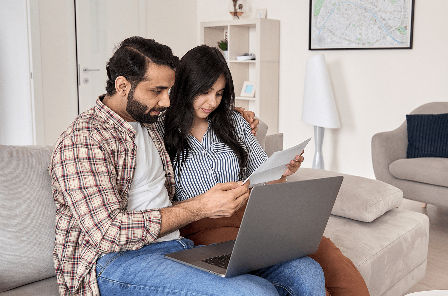 Couple sat together in front of their laptop reading an important document