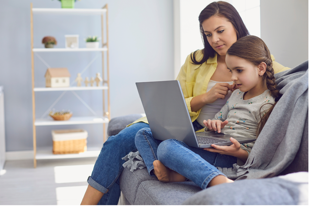Mother and daughter sat together on the sofa using a laptop