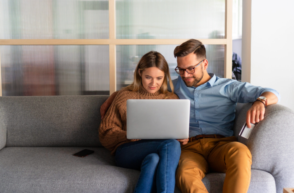 Couple sat together on the sofa on their laptop