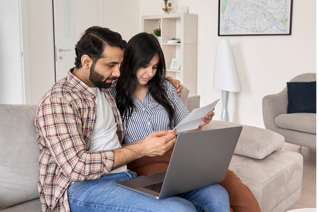 Couple sat together in front of their laptop reading an important document